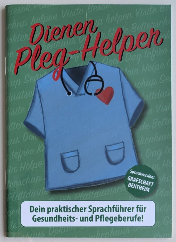 Cover des grünen Sprachführers „Dienen Pleg-Helper“ mit einer Illustration eines blauen Pflegekittels mit Stethoskop und rotem Herz, dem Hinweis „Sprachversion: Grafschaft Bentheim“ und dem Untertitel „Dein praktischer Sprachführer für Gesundheits- und Pflegeberufe!“.