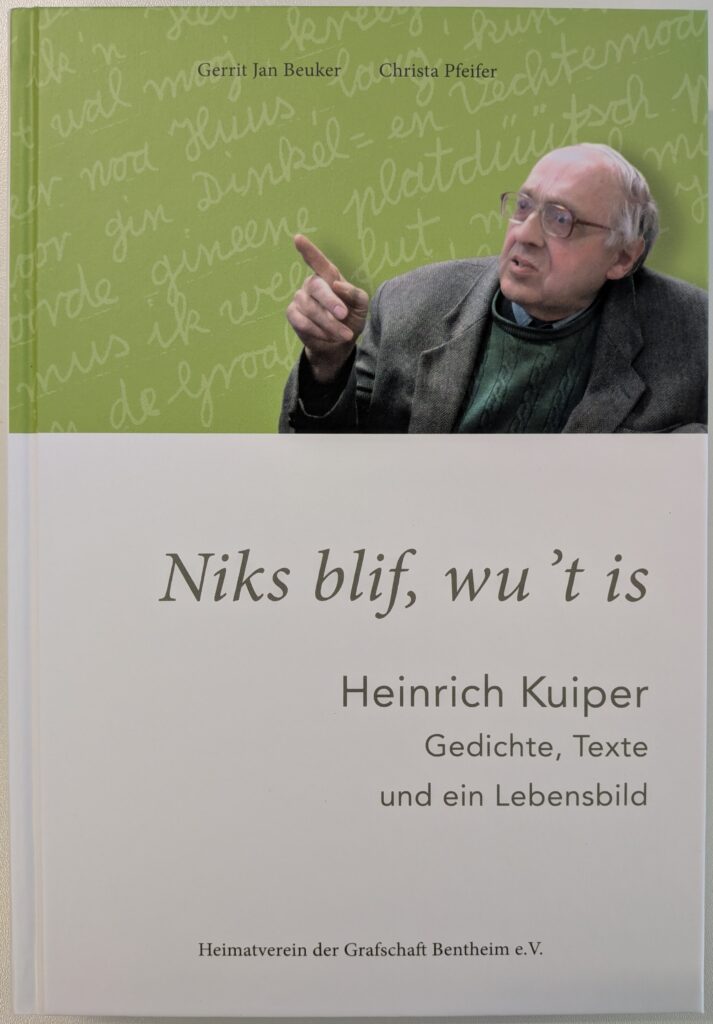Buchcover „Niks blif, wu 't is – Heinrich Kuiper: Gedichte, Texte und ein Lebensbild“ von Gerrit Jan Beuker und Christa Pfeifer, herausgegeben vom Heimatverein der Grafschaft Bentheim e.V., mit einem Foto des gestikulierenden Heinrich Kuiper vor grünem Hintergrund mit plattdeutscher Handschrift.
